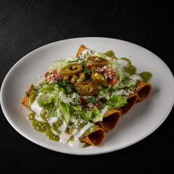 Fuego Cravings - Four crispy birria taquitos topped with mozzarella, sour cream, guac sauce, onion, cilantro & jalapeños + consommé.