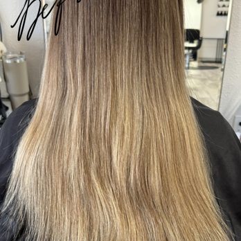 Arrow & Mane - A woman with long, straight blonde hair is seated in a salon, with a mirror and salon equipment visible in the background. - Hair Extensions Near Me - Tracy, California