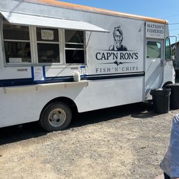 ows a man sitting at a table in front of a food truck