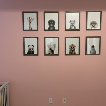 New Generation Painters - A pink-painted wall features eight framed animal portraits arranged in two rows, with a crib partially visible on the left. - Painters Near Me