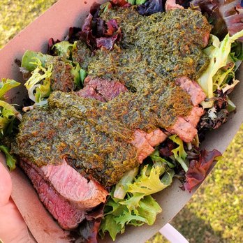 Barcelona OntheGo - Sirloin steak with chimichurri on top of greens - Spanish Near Me