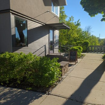 Collective Flow - Collective Flow will fool ya from the outside! Be brave! Collect yourself and go inside! - Exterior view of a contemporary building with large windows, a sidewalk, and surrounding greenery on a clear, sunny day. - Yoga Near Me - Milwaukee, Wisconsin