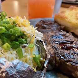 Steer'n Stein - Rib Eye Steak comes with 2 sides (Salad - not pictured, Baked Potato) and Garlic Bread