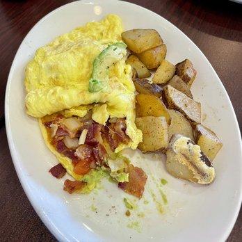 Simone's - Avocadonator Omelet Avocadonator Omelet - A breakfast plate features a folded omelette with vegetables and bacon, accompanied by roasted potatoes, on a white dish. - Burgers Near Me - Mount Lebanon, Pennsylvania
