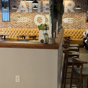 Amber Ox Public House - Exposed brick and mustard-colored banquettes inside Amber Ox. - American Near Me - Williamsburg, Virginia