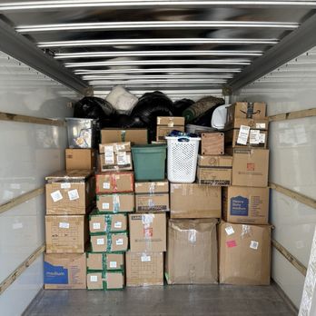 Heroic Movers - A truck interior loaded with cardboard boxes, plastic bins, and black garbage bags, with some items stacked at the back. - Movers Near Me