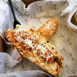 Humo Charcutería - Sausage Sandwich, topped off with Bacon and Cheese,  with a side of Corn on the Cob