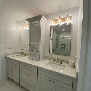 Fresh Kitchen & Bath Design - Elegant bathroom 2 - pale gray vanity with storage tower and gold accents via lighting and pulls - Kitchen & Bath Near Me Fresh Kitchen & Bath Design - Elegant bathroom 2 - pale gray vanity with storage tower and gold accents via lighting and pulls - Kitchen & Bath Near Me