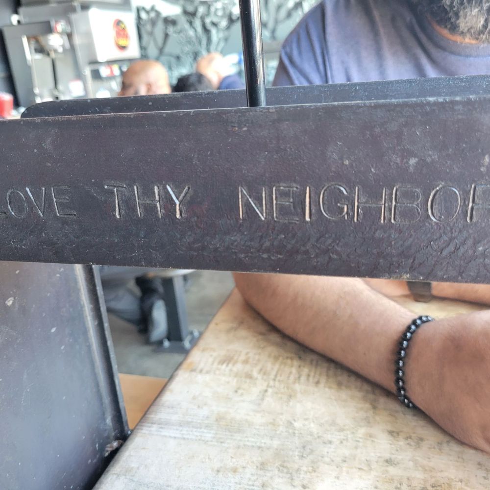 Dog Haus - a man holding a sign that says love thy neighbor - Burgers Near Me - Palmdale, California Dog Haus - a man holding a sign that says love thy neighbor - Burgers Near Me - Palmdale, California