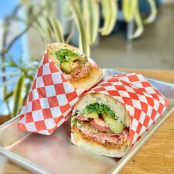 Work in Progress - SPICY SANDO Spicy salami, romesco, pickled jalapeños, cornichons, tomatoes, chimichurri, arugula, Beemster cheese, herbed aioli