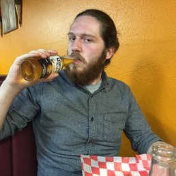 a man sitting at a table drinking from a bottle a man sitting at a table drinking from a bottle
