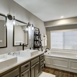 Sisu Painting - Bathroom remodel using the existing cabinets. We painted the vanity dark and tub wood white. This updated the style and work with the design