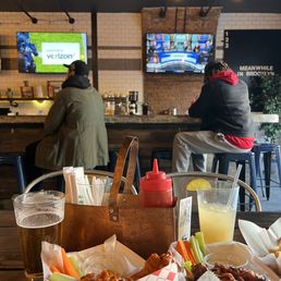 two people sitting at a bar with food and drinks