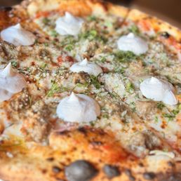 Fennel Sausage Pizza - A pizza with a golden-brown crust, topped with dollops of white cheese, herbs, and sausage pieces, served on a plate.