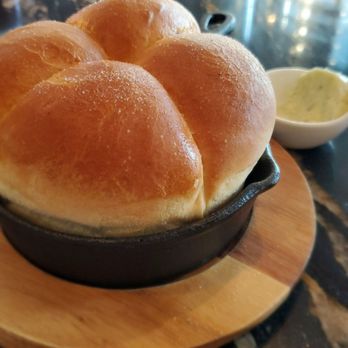 Atlas Steak + Fish - Freshly baked dinner roll in cast iron skillet with herb butter on the side - Steakhouses Near Me - Edmonton, Alberta Atlas Steak + Fish - Freshly baked dinner roll in cast iron skillet with herb butter on the side - Steakhouses Near Me - Edmonton, Alberta