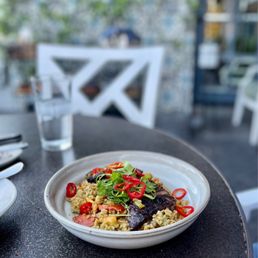 Korean Prime Skirt Steak - A dish featuring Korean prime skirt steak with rice, garnished with sliced red chili peppers and fresh greens, on a dark outdoor table.