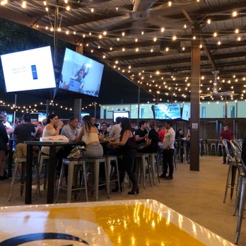 Little Woodrow's Tomball - Outside sitting are under tin roof. Approx 6 long tables , 6 four topper tables along the side. - Sports Bars Near Me - Tomball, Texas