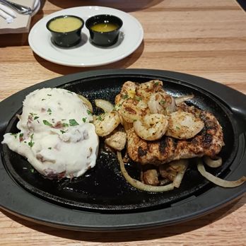 Applebee's Grill + Bar - Blackened, sizzling chicken and shrimp entree with garlic mashed potatoes.  In the small black containers, the left is garlic butter - Sports Bars Near Me - Nottingham, Maryland