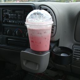 a drink in a plastic cup on the dashboard of a car