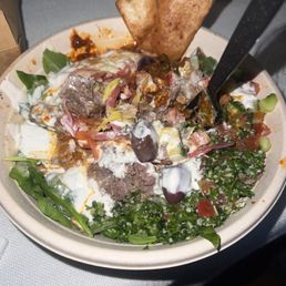 Bowl with rice, half romaine half arugula half chicken half beef and various sauces, toppings and dressing!