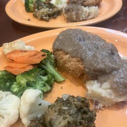 Chicken dinner with gravy, mashed potatoes, stuffing and vegetables entree split in half