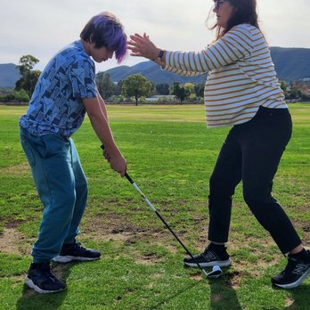 Murrieta Valley Golf Range - Coach Jenn positioning her student for a successful swing! - Golf Near Me - Murrieta, California Murrieta Valley Golf Range - Coach Jenn positioning her student for a successful swing! - Golf Near Me - Murrieta, California