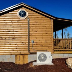 Day's Heating & Air - An exterior view of a log cabin with a small porch and an octagonal attic window, beneath a bright blue sky...