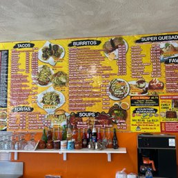 A colorful menu board at Los 6 Hermanos in Bernalillo, NM, features Mexican dishes like tacos, burritos, and quesadillas, with prices and options.