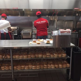 Five Guys - a man in a red shirt and a woman in a red shirt are preparing doughnuts in a commercial kitchen - Fast Food Near Me - Johnston, Rhode Island