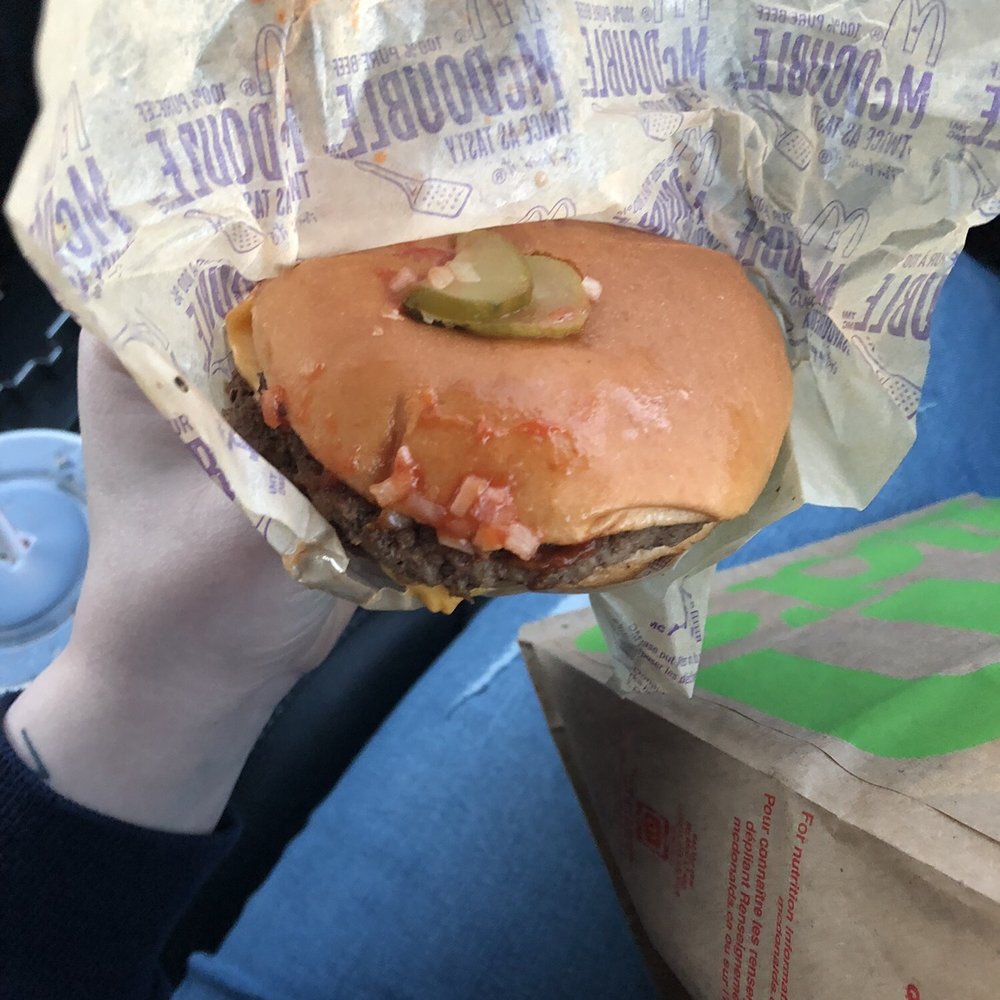 a person holding a hamburger wrapped in foil a person holding a hamburger wrapped in foil