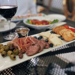a plate of meat, cheese, olives, and bread