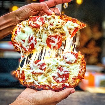Bowstring Pizza and Brewyard - a hand holding a piece of pizza - Bars Near Me - Raleigh, North Carolina Bowstring Pizza and Brewyard - a hand holding a piece of pizza - Bars Near Me - Raleigh, North Carolina