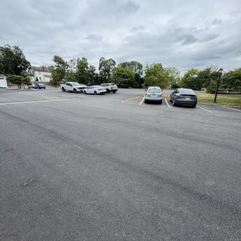Delicious Heights - Huge parking area - A parking lot with several parked cars, surrounded by trees and residential buildings under a cloudy sky. - Bars Near Me - Bedminster, New Jersey
