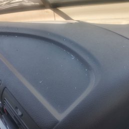 After windshield replacement all the dashboard has sharp glass debris that I had to clean and I got cut in my skin - The dashboard of a vehicle shows sharp glass debris from a recent windshield replacement, with visible small glass fragments on the surface.