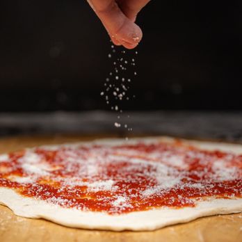 Lenny's Coal Fired Pizza - a person sprinkling pepper on a pizza - Pizza Near Me - Valparaiso, Indiana Lenny's Coal Fired Pizza - a person sprinkling pepper on a pizza - Pizza Near Me - Valparaiso, Indiana