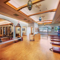 The Pilates Principle - The Pilates Towers are pictured on the right. Cadillacs at far end, ladder barrels center, and reformer area to left.