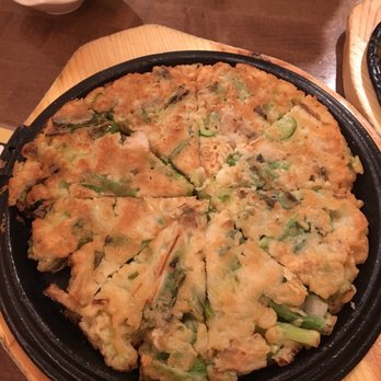Ssome - a pizza on a wooden table with a bowl of sauce - Korean Near Me - Calgary, Alberta
