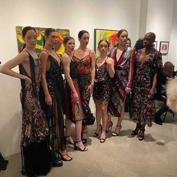 Foundry Gallery - Seven models stand in a line at an art gallery, wearing diverse, patterned dresses and high heels, with abstract artwork in the background. - Art Galleries Near Me - Washington, DC, District of Columbia