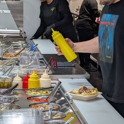 Potato Bar - Balal, the manager, holding a squeeze bottle of sauce