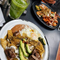 Roble de Raíz a la Mesa - Chilaquiles verdes,huevo, avocado, refried beans & steak, Jugo verde(spinach, orange, celery, cactus) Chilaquiles Rojos w/Chile Reyeno OJ