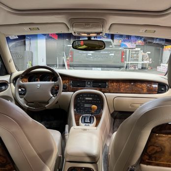 Wrap Zone - The photo shows the interior of a vehicle with beige leather seats, wood trim on the dashboard and center console, and a gear shift. The view is from the back seats looking forward. - Car Window Tinting Near Me - Addison, Illinois