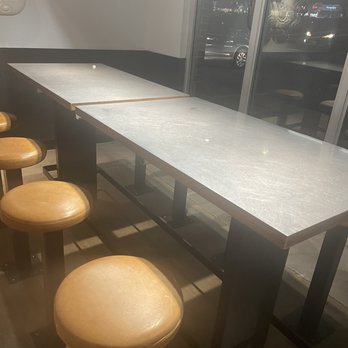 Chipotle Mexican Grill - Nasty table that needed to be wiped down. - Inside a restaurant, there are two high-top tables with brown stools, positioned near large glass windows showing a nighttime street scene. - Mexican Near Me - Hanover, Maryland