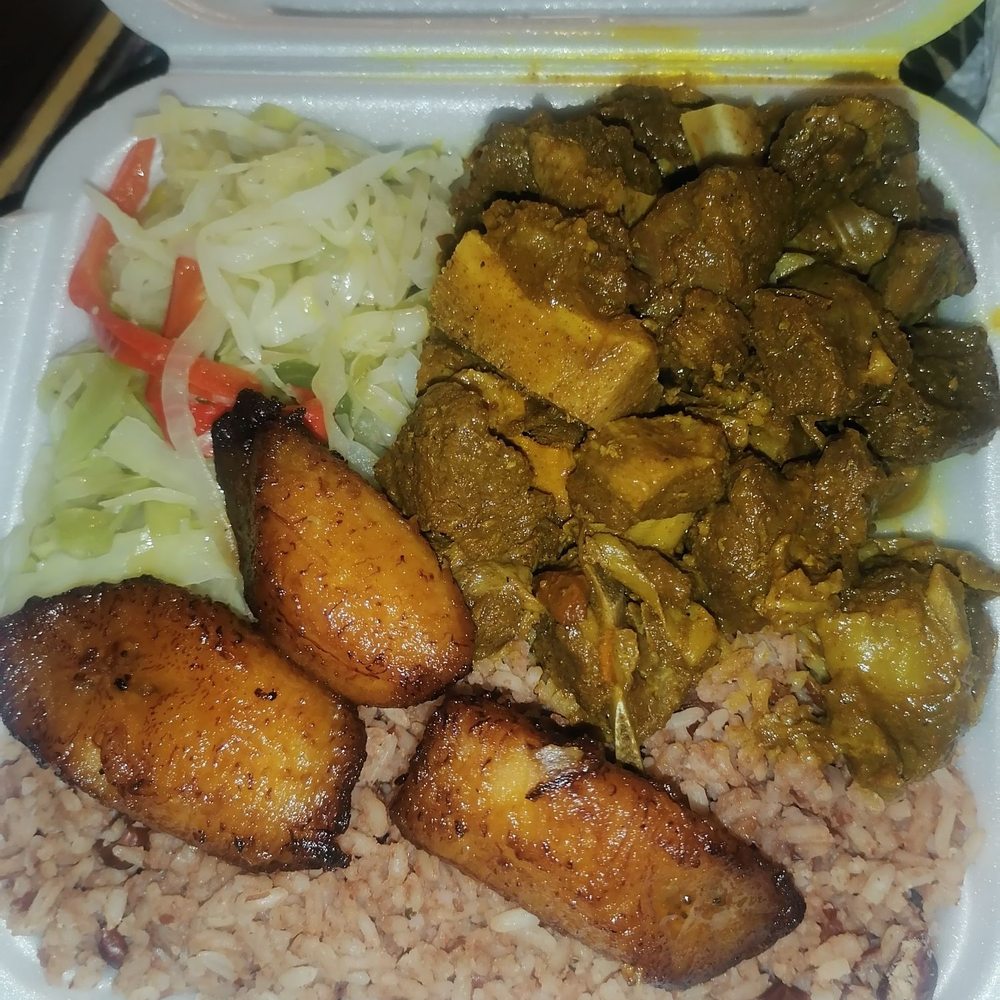 Curry Goat with rice and peas, steamed cabbage and plantains.