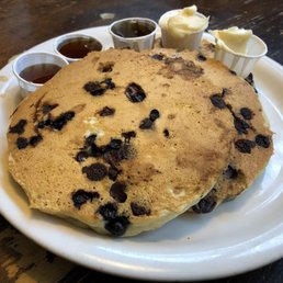Fluffy vegan pancakes with blueberries and chocolate chips, vegan butter and maple syrup