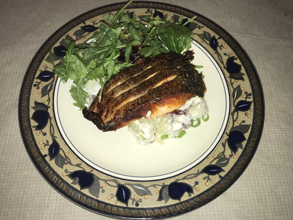 Crispy salmon, baked potato salad, and spring greens with lemon