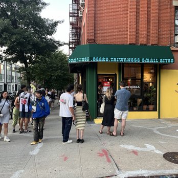 Formosa - Launch line was crazy by time I left - A group of people stand outside a Taiwanese restaurant with a green awning, on a city sidewalk near a crosswalk. - Taiwanese Near Me - Brooklyn, New York