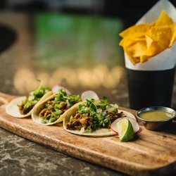Flanker Kitchen + Sports Bar - Carnitas Tacos made with overnight-cooked pork shoulder, warm corn tortillas, cilantro and onion and salsa verde