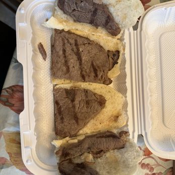 The Lantern - Steak sandwich - Four beef steak sandwiches with grilled beef and bread are arranged in a white takeout container on a floral tablecloth. - New American Near Me - Wanaque, New Jersey