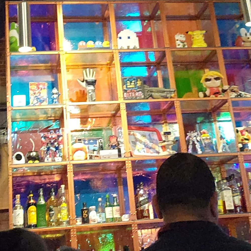 Bit Bar Salem - Behind the bar was this nice display. I loved the Nintendo and Pac Man items. Not seen are the cartoons playing on TVs. - Bars Near Me - Salem, Massachusetts