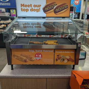 Circle K - Tornadoes - A roller grill displaying hot dogs and sausage rolls at a convenience store, with promotional signs advertising prices and flavors. - Convenience Stores Near Me - Stouffville, Ontario